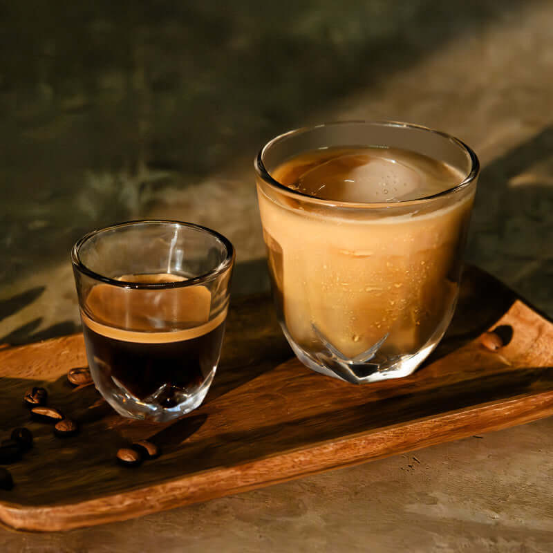 Stellar latte glass and espresso cups filled with coffee on a wooden board